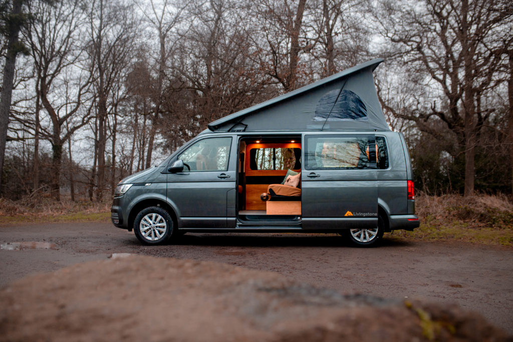 Volkswagen Livingstone converted campervan by Rolling Homes. Shown with roof extension and open side door showing illuminate living area.